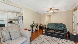 Living area featuring a ceiling fan, light wood floors, and ornamental molding