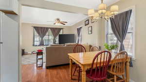 Dining space featuring a chandelier, crown molding, healthy amount of natural light, wood floors, and a ceiling fan