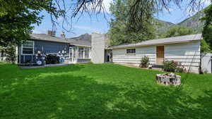Rear view of property with a lawn, a fire pit, and a view of the detached garage