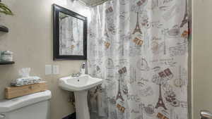 Full bathroom featuring toilet and curtained shower