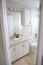 Bathroom featuring vanity, toilet, tile patterned floors, and washtub / shower combination