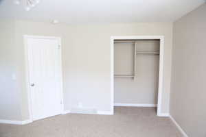 Unfurnished bedroom with carpet floors, a closet, and baseboards
