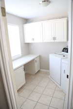 Laundry area with cabinet space, washing machine and clothes dryer, and light tile patterned floors