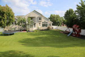 Back of property with a trampoline, a playground, and stucco siding