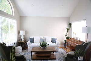 Living room with healthy amount of natural light, high vaulted ceiling, light wood finished floors, recessed lighting, and baseboards