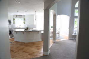 Kitchen featuring stainless steel appliances, arched walkways, backsplash, open shelves, and white cabinets