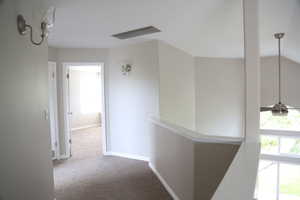 Hallway featuring carpet flooring, an upstairs landing, and baseboards
