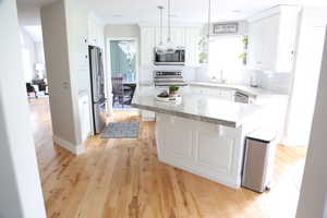 Kitchen featuring appliances with stainless steel finishes, plenty of natural light, white cabinetry, and tasteful backsplash