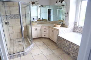 Bathroom featuring double vanity, a stall shower, tile patterned floors, and a bath