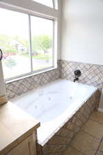 Full bathroom featuring plenty of natural light, a whirlpool tub, and tile patterned flooring