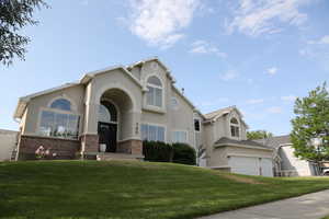 View of front of house with a front yard, stucco siding, and brick siding