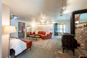Carpeted living area featuring a wood stove and ceiling fan