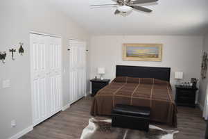 Bedroom featuring multiple closets, wood finished floors, baseboards, vaulted ceiling, and ceiling fan