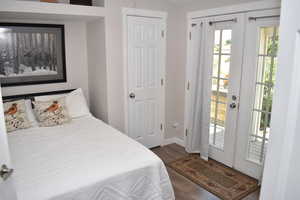 Bedroom with wood finished floors, access to exterior, and baseboards