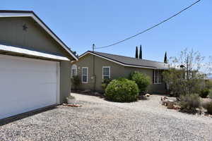 View of property exterior featuring a garage, driveway, and metal roof