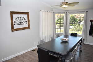 Dining space with baseboards, dark wood-style flooring, ceiling fan, and vaulted ceiling