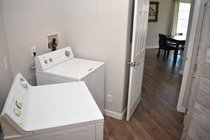 Laundry area with independent washer and dryer, dark wood-style floors, and baseboards