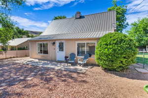 Back of property featuring stucco siding, a patio, a standing seam roof, metal roof, and a chimney