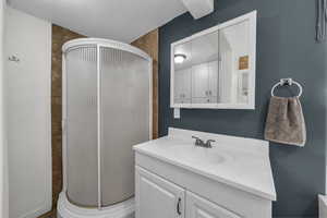 Full bath with a shower stall, vanity, and a textured ceiling