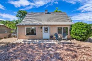 Back of property with a trampoline, stucco siding, a patio, metal roof, and a chimney