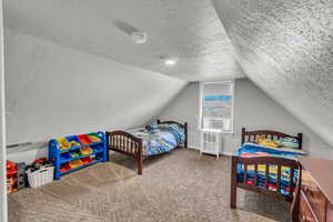 Bedroom with a textured ceiling, lofted ceiling, carpet, cooling unit, and baseboards