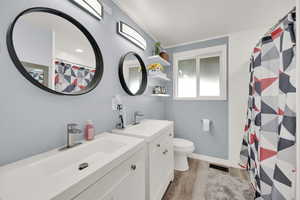 Full bath featuring wood finished floors, vanity, toilet, a shower with shower curtain, and baseboards