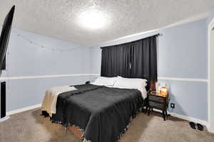 Carpeted bedroom with a textured ceiling and baseboards