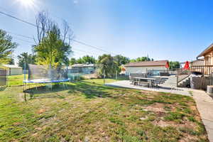 View of yard with a trampoline, a patio area, and a wooden deck
