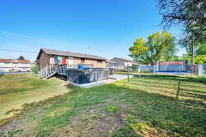 Rear view of house featuring a hot tub, a trampoline, and a deck