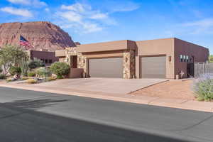 Southwest-style home featuring an attached garage, stucco siding, a mountain view, stone siding, and driveway