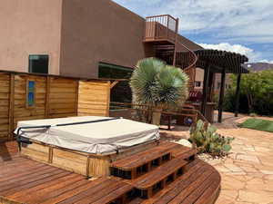 Deck with a covered hot tub and a patio