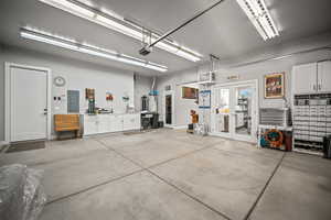 Garage with electric panel, a garage door opener, strapped water heater, and a sink
