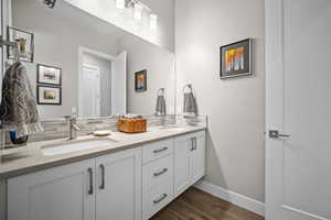 Full bathroom featuring double vanity, backsplash, wood finished floors, and baseboards