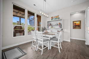 Dining room featuring dark wood-type flooring, baseboards, and a chandelier