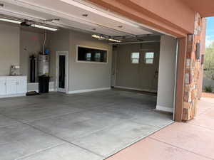 Garage featuring secured water heater, a garage door opener, and concrete driveway