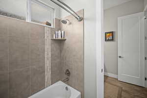 Full bath with shower / bath combination, wood finished floors, and baseboards