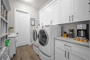 Washroom with independent washer and dryer, cabinet space, and dark wood finished floors