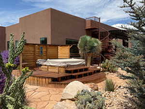 Back of property featuring a deck, stucco siding, and a covered hot tub