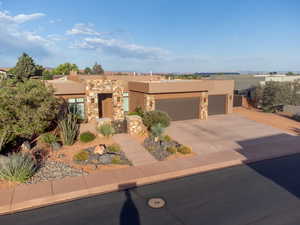 Adobe home featuring stucco siding, an attached garage, driveway, a gate, and stone siding