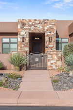 Entrance to property with a gate, stucco siding, and stone siding