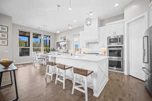 Kitchen featuring appliances with stainless steel finishes, a sink, white cabinets, a breakfast bar, and backsplash