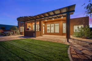 Rear view of house with stucco siding, area for grilling, a patio area, and a lawn
