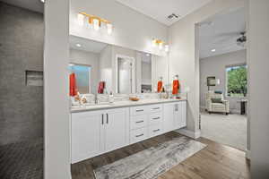 Full bathroom with double vanity, wood finished floors, tasteful backsplash, ceiling fan, and a tile shower