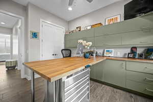 Kitchen featuring wood counters, green cabinets, dark wood finished floors, an office area, and recessed lighting