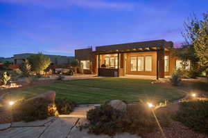 Back of house featuring stucco siding, a lawn, a patio, and a pergola