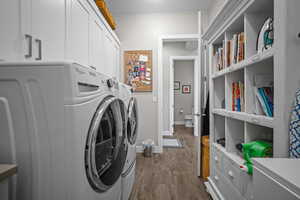 Laundry room with cabinet space, separate washer and dryer, dark wood-type flooring, and baseboards