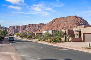 View of asphalt road featuring sidewalks, a mountain view, and curbs