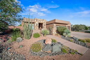 Pueblo-style house with a fenced front yard, driveway, stucco siding, and an attached garage