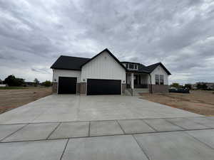 Modern farmhouse style home with board and batten siding, an attached garage, covered porch, concrete driveway, and roof with shingles