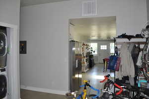 Laundry room featuring estacked washer and dryer, light wood-style flooring, and baseboards